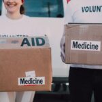 Volunteers holding boxes labeled 'AID' and 'Medicine', preparing donations. - Photo by RDNE Stock project on Pexels