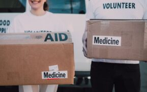 Volunteers holding boxes labeled 'AID' and 'Medicine', preparing donations. - Photo by RDNE Stock project on Pexels