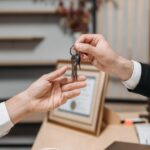 Detailed view of hands exchanging keys in a professional office environment, symbolizing real estate or business transactions. - Photo by Pavel Danilyuk on Pexels