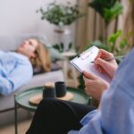Unrecognizable professional therapist writing on clipboard while sitting against male client lying on couch on blurred background during mental health therapy - Photo by SHVETS production on Pexels