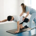 A physiotherapist guides a patient's exercise on a mat in a Vilnius gym. - Photo by Funkcinės Terapijos Centras on Pexels