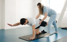 A physiotherapist guides a patient's exercise on a mat in a Vilnius gym. - Photo by Funkcinės Terapijos Centras on Pexels
