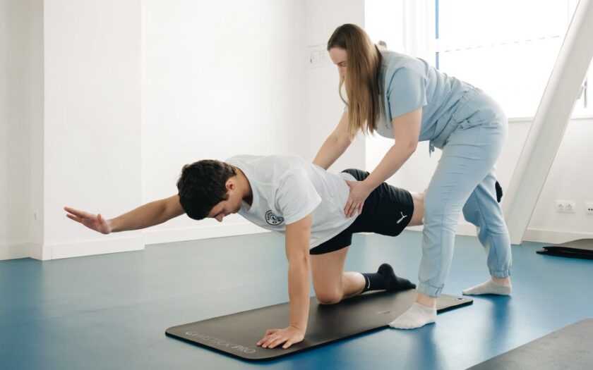 A physiotherapist guides a patient's exercise on a mat in a Vilnius gym. - Photo by Funkcinės Terapijos Centras on Pexels