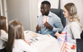 Teacher guiding diverse students in an English language lesson with a British flag card. - Photo by Gustavo Fring on Pexels