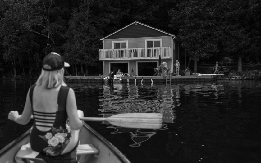 Woman paddling a canoe towards a lakeside house, capturing summer relaxation. - Photo by Paige Thompson on Pexels
