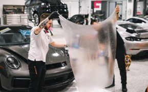 Two professionals applying protective film to a luxury car in a modern garage. - Photo by WAVYVISUALS on Pexels